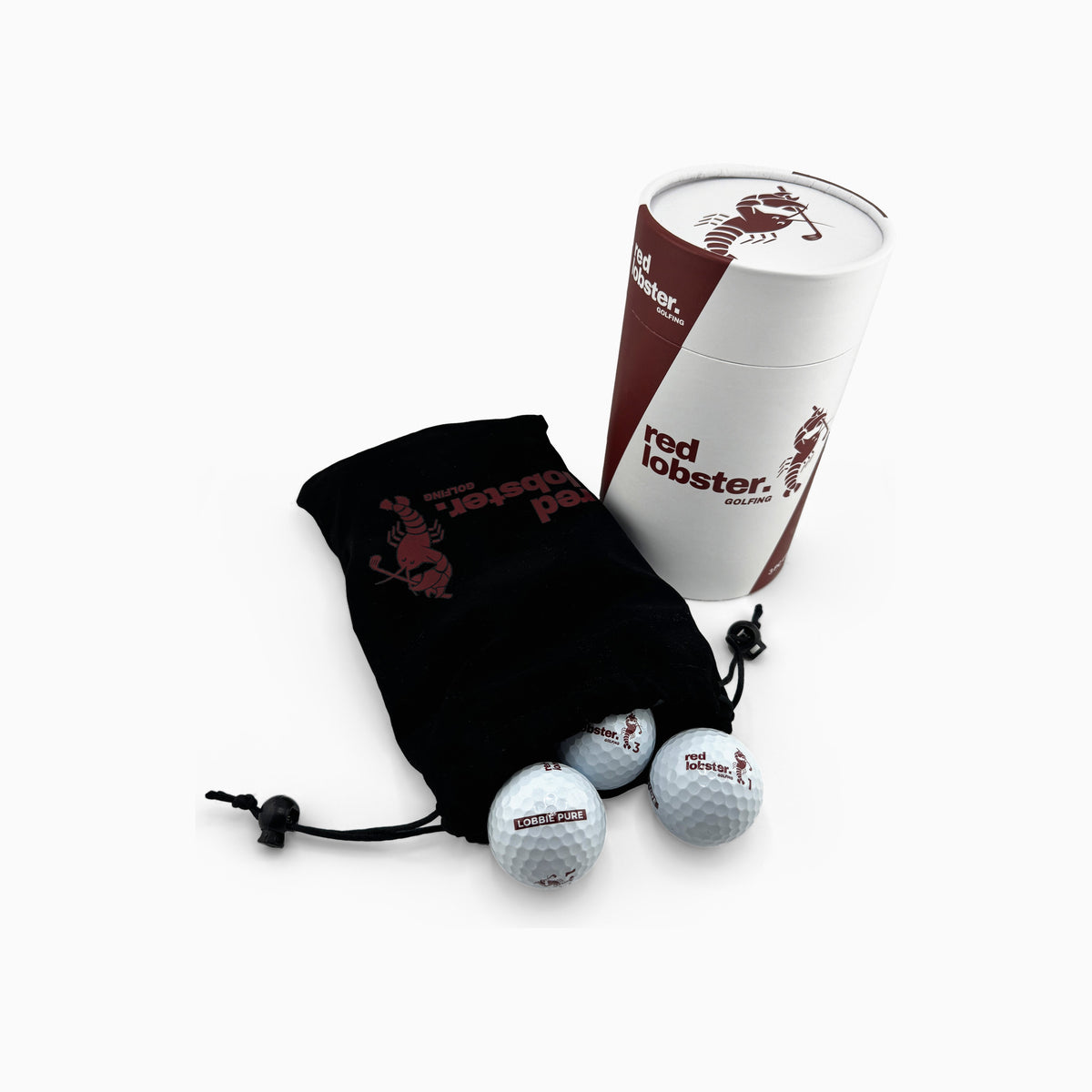 Lobbie PURE Geschenk-Tube von Red Lobster Golfing, davor ein schwarzes Samtsäckchen, aus dem drei weiße Golfbälle rollen