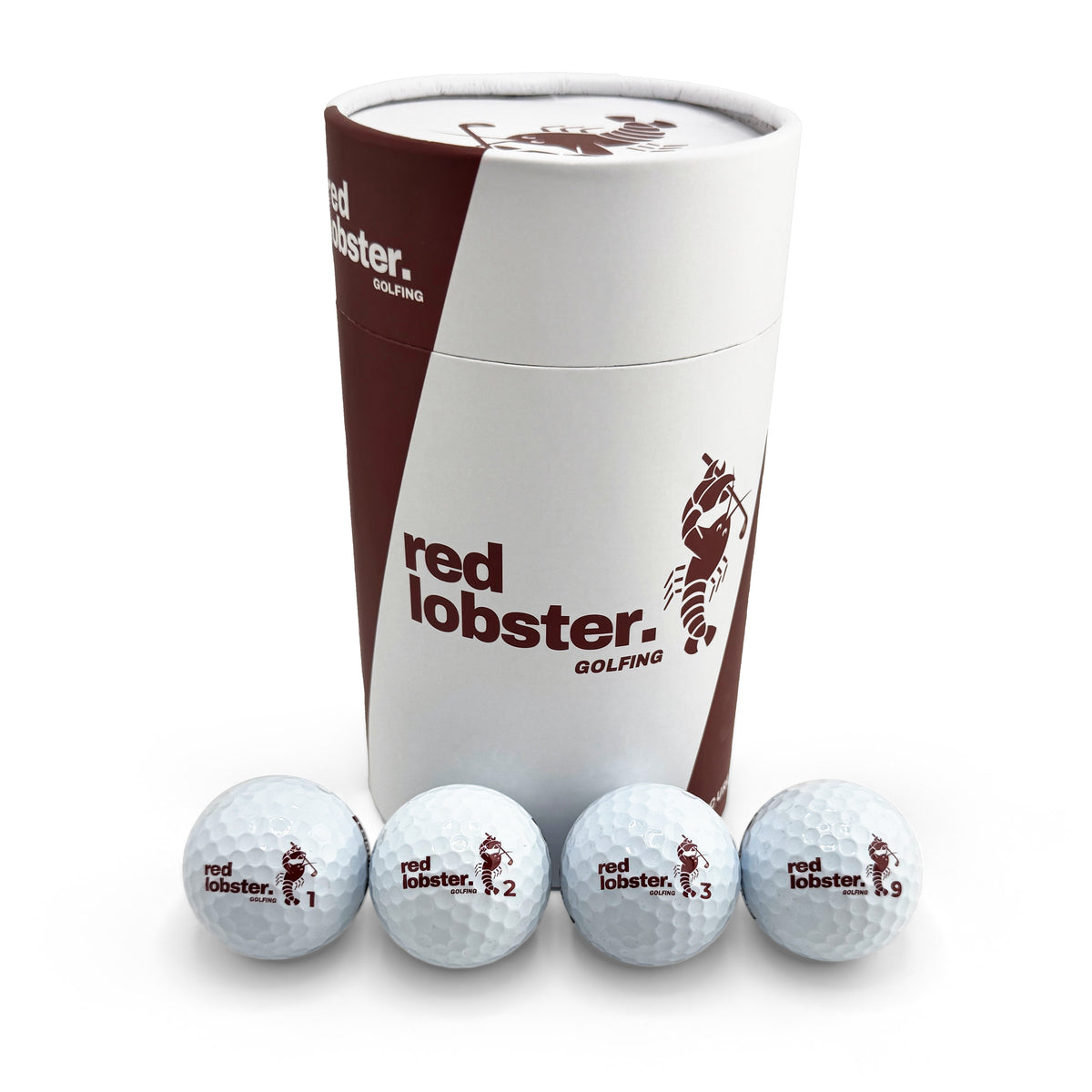 Vier weiße Lobbie PURE Golfbälle mit Red-Lobster-Golfing-Logo und den Nummern 1, 2, 3 und 9 vor der Geschenk-Tube